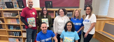 Volunteers holding books and smiling